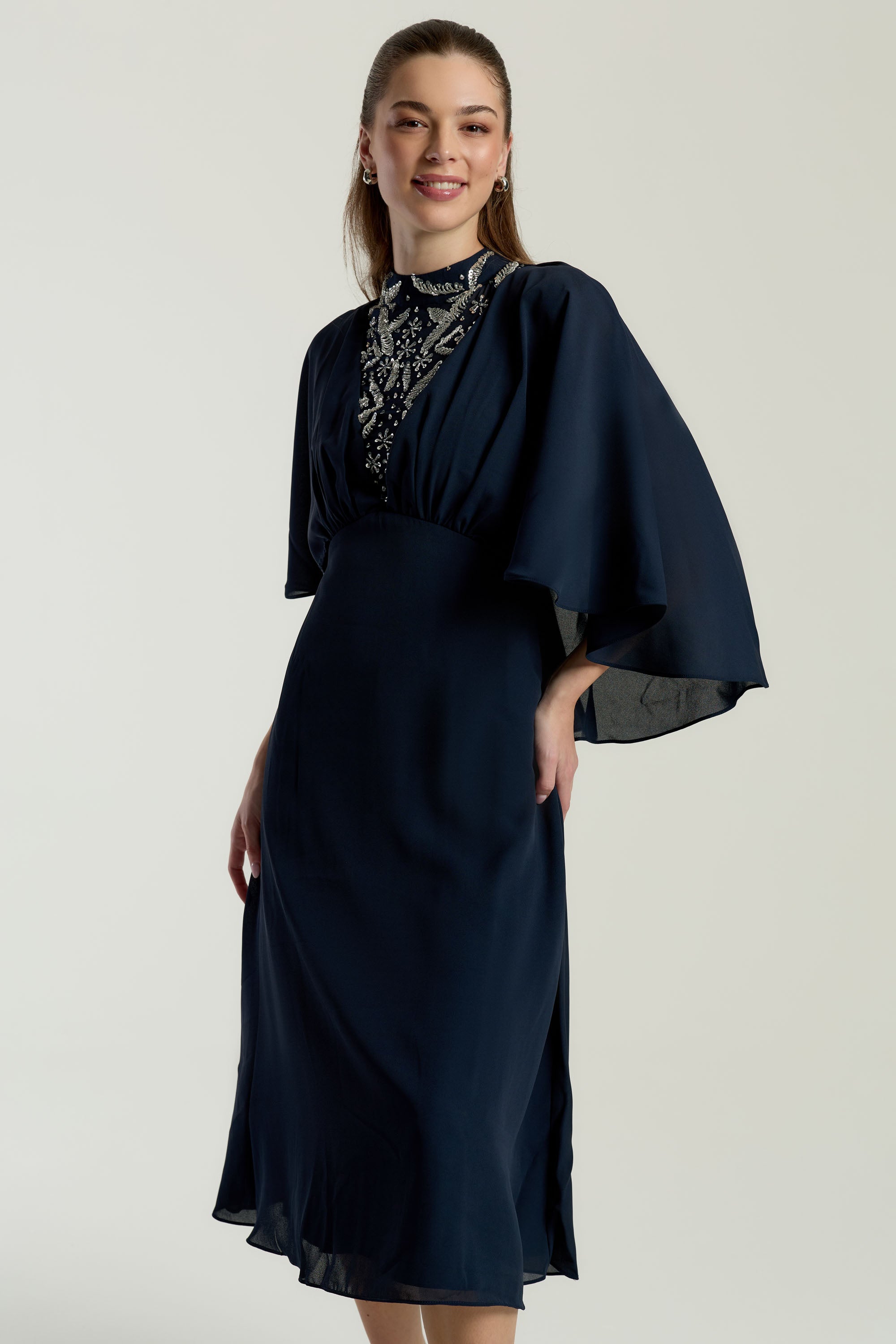 Alani navy embellished cape sleeve midi dress by Frock and Frill with high neckline, silver embellishment and flowing cape sleeves designed for elegant occasion wear styling