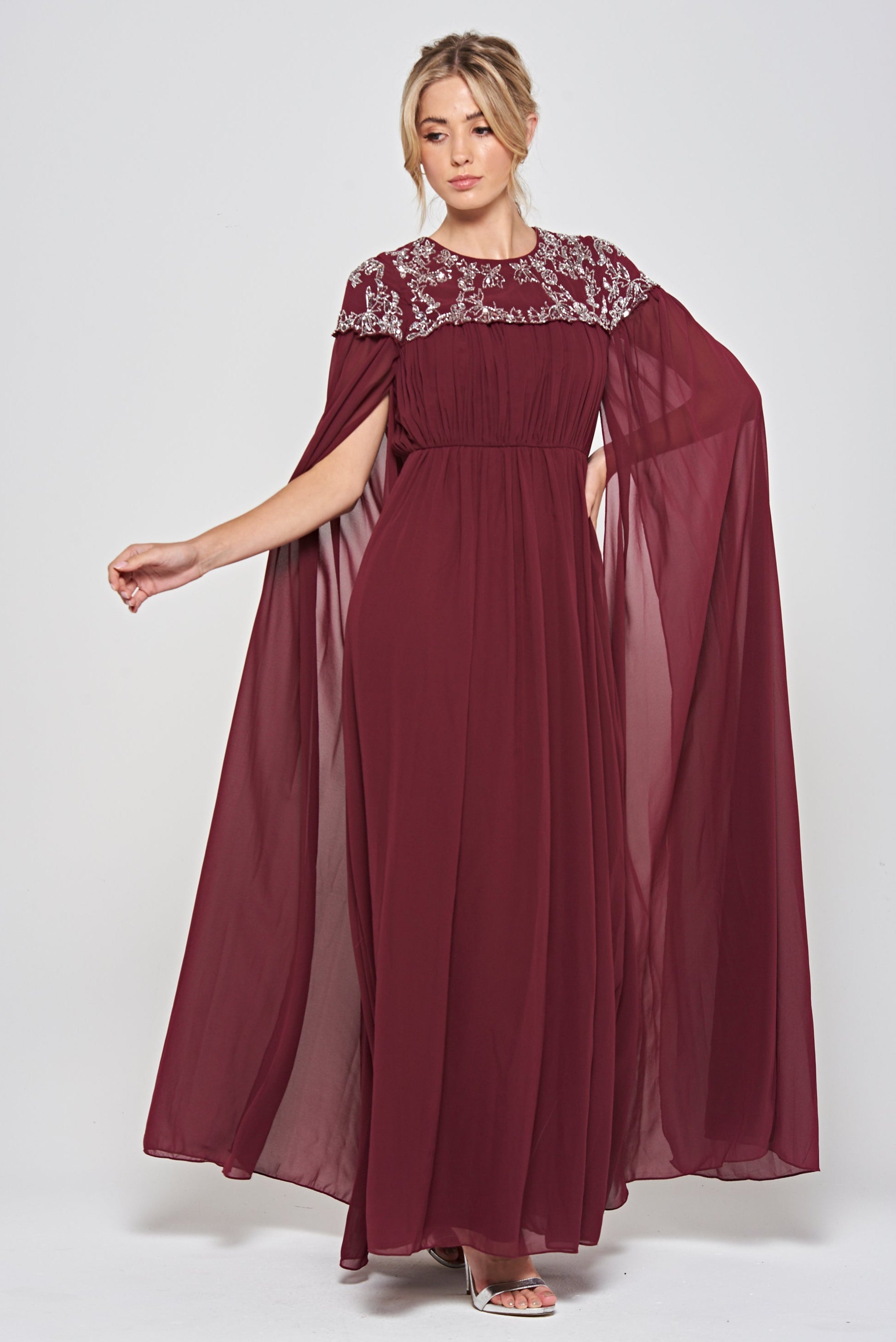 Frock & Frill Aruna burgundy embellished cape maxi dress with sparkling beaded bodice, flowing chiffon cape sleeves, and elegant full-length silhouette—ideal for weddings and formal events.