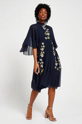 Maeve navy floral embroidered midi dress by Frock and Frill with high neckline, flowing cape sleeves, and elegant silhouette.
