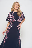 Navy floral embroidered maxi dress with pink detailing, worn by a model. Features flutter sleeves, a fitted waist and a flowing full-length skirt—perfect for weddings, evening occasions and special events.