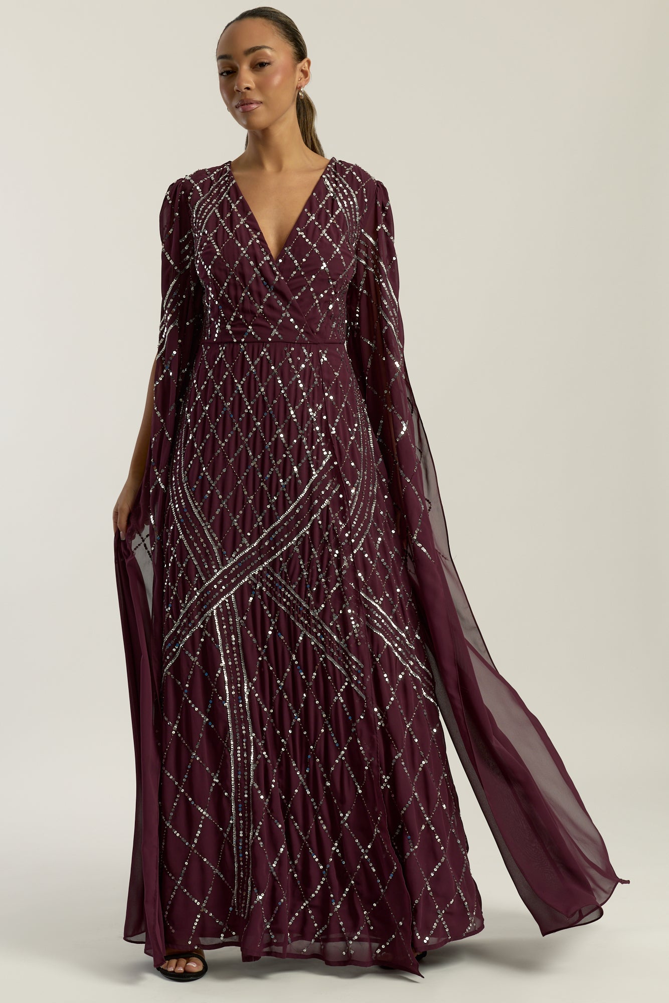 Simone fig sequin cape sleeve maxi dress with plunging V neckline, silver criss-cross sequin detailing and flowing full-length silhouette for statement occasion wear styling