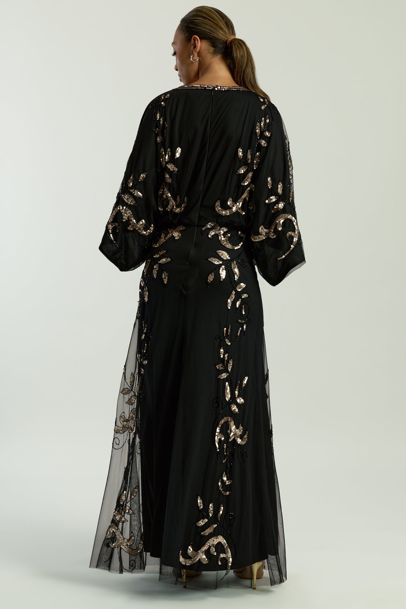 Black maxi dress with gold sequin floral embellishment, flowing sheer sleeves and full-length silhouette, Ambretta by Frock and Frill.