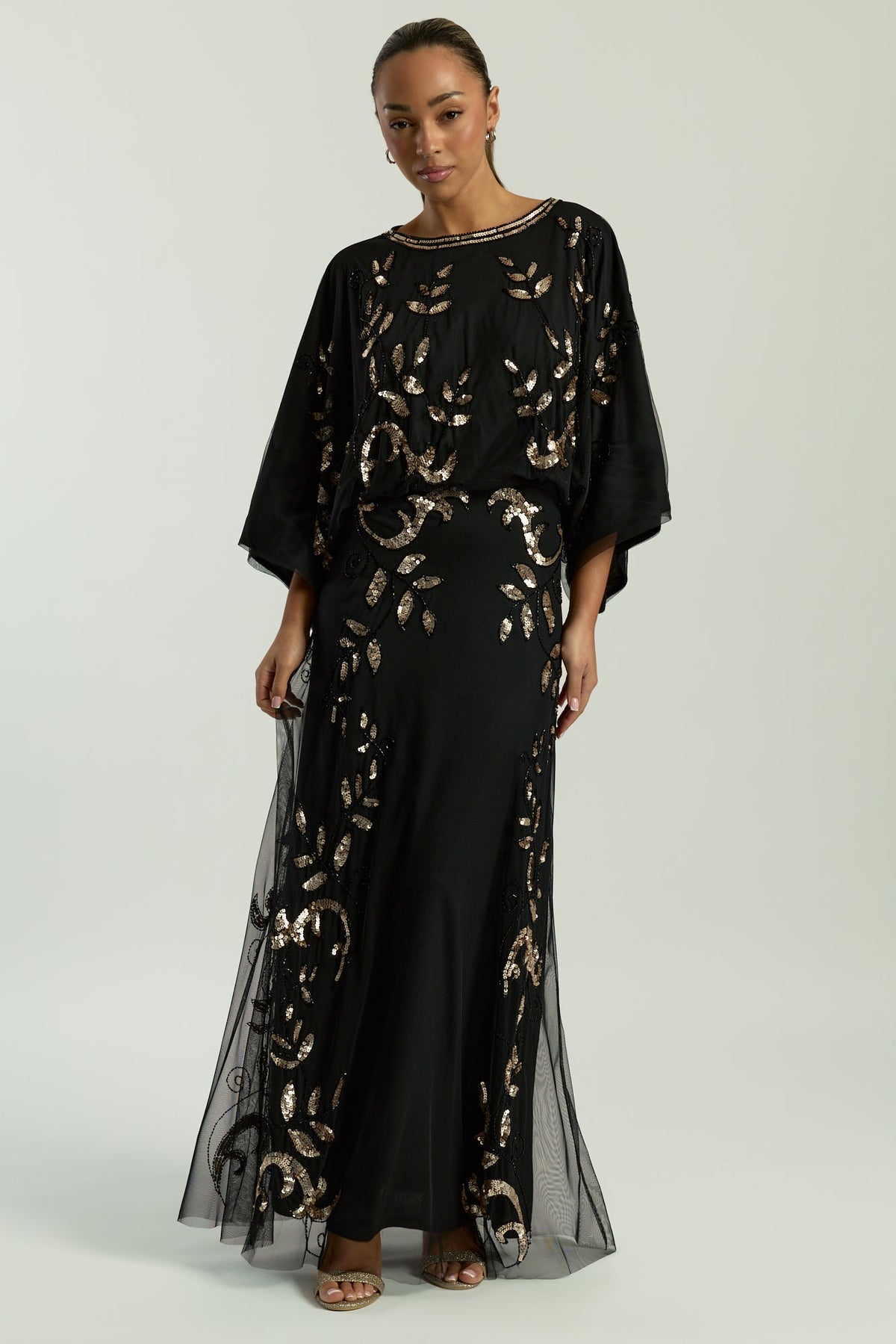 Black maxi dress with gold sequin floral embellishment, flowing sheer sleeves and full-length silhouette, Ambretta by Frock and Frill.