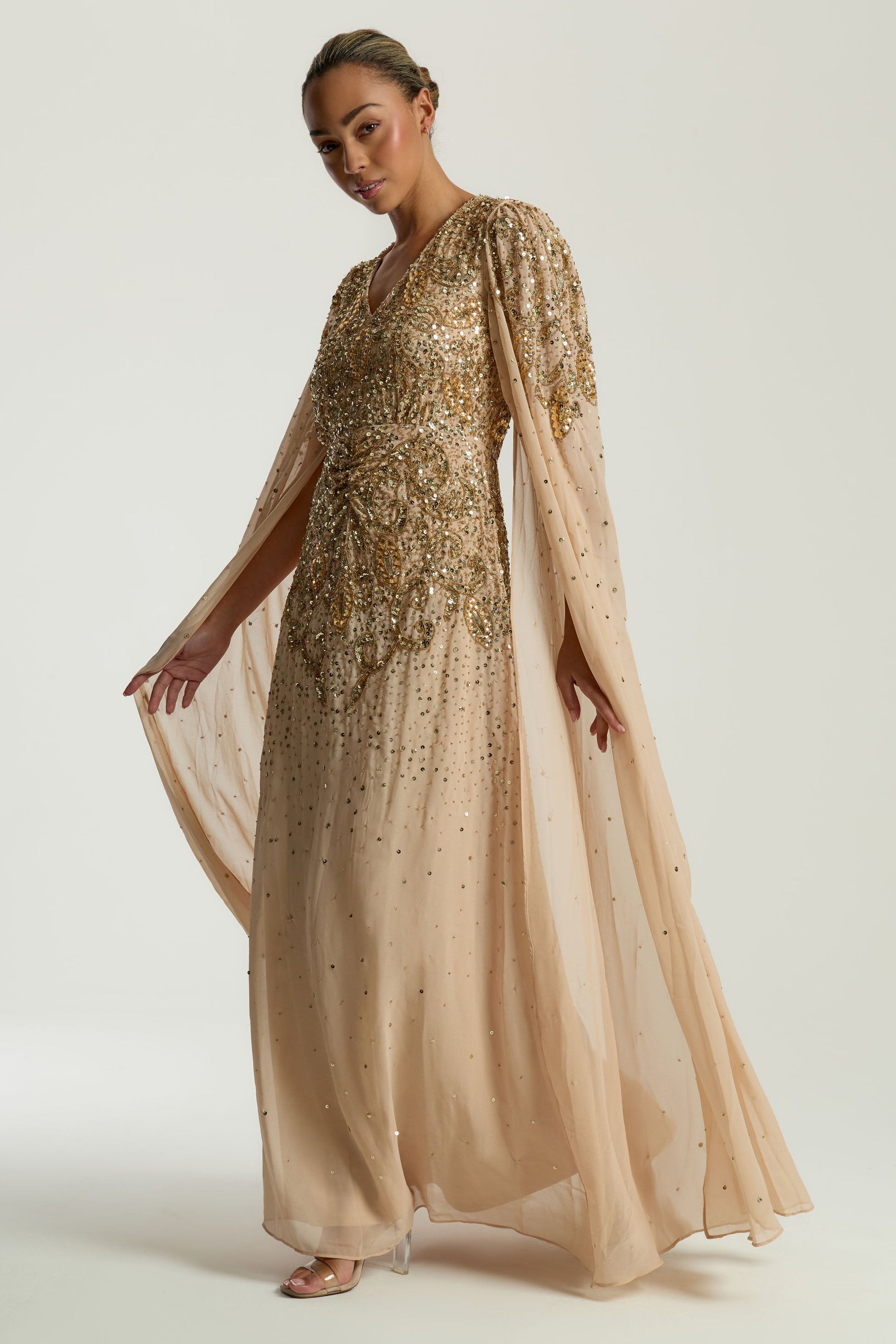 Donna gold embellished maxi dress with flowing cape sleeves, intricate beaded bodice and scattered sequins cascading to the hem.