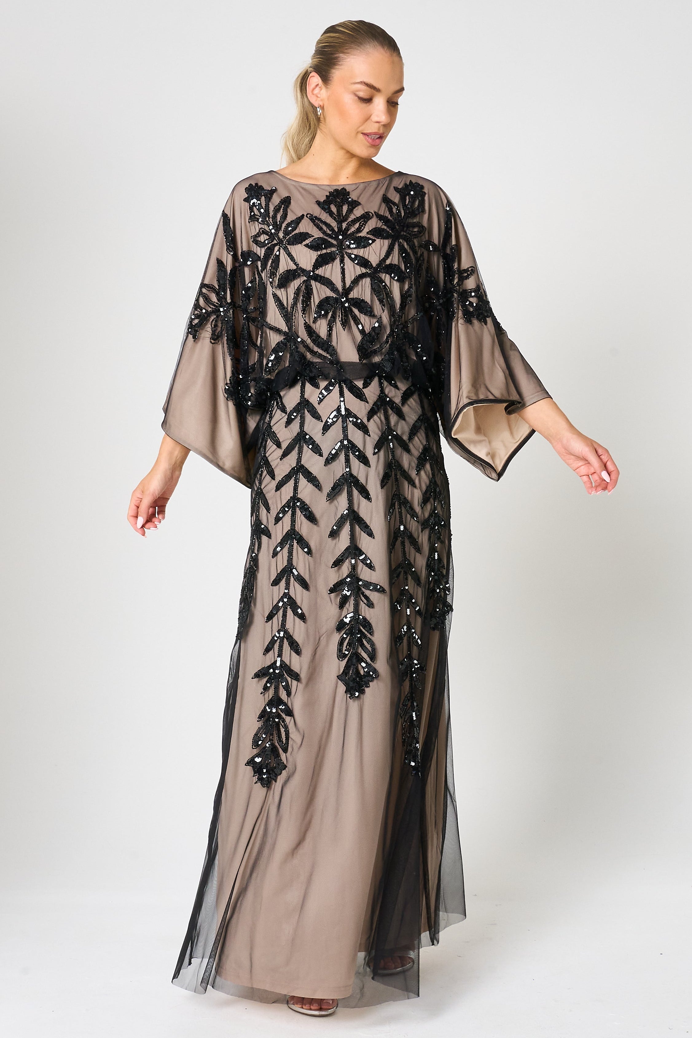 Elva sequin maxi dress with black leaf motif embellishment on a neutral base, batwing sleeves and flowing silhouette for statement occasion wear styling