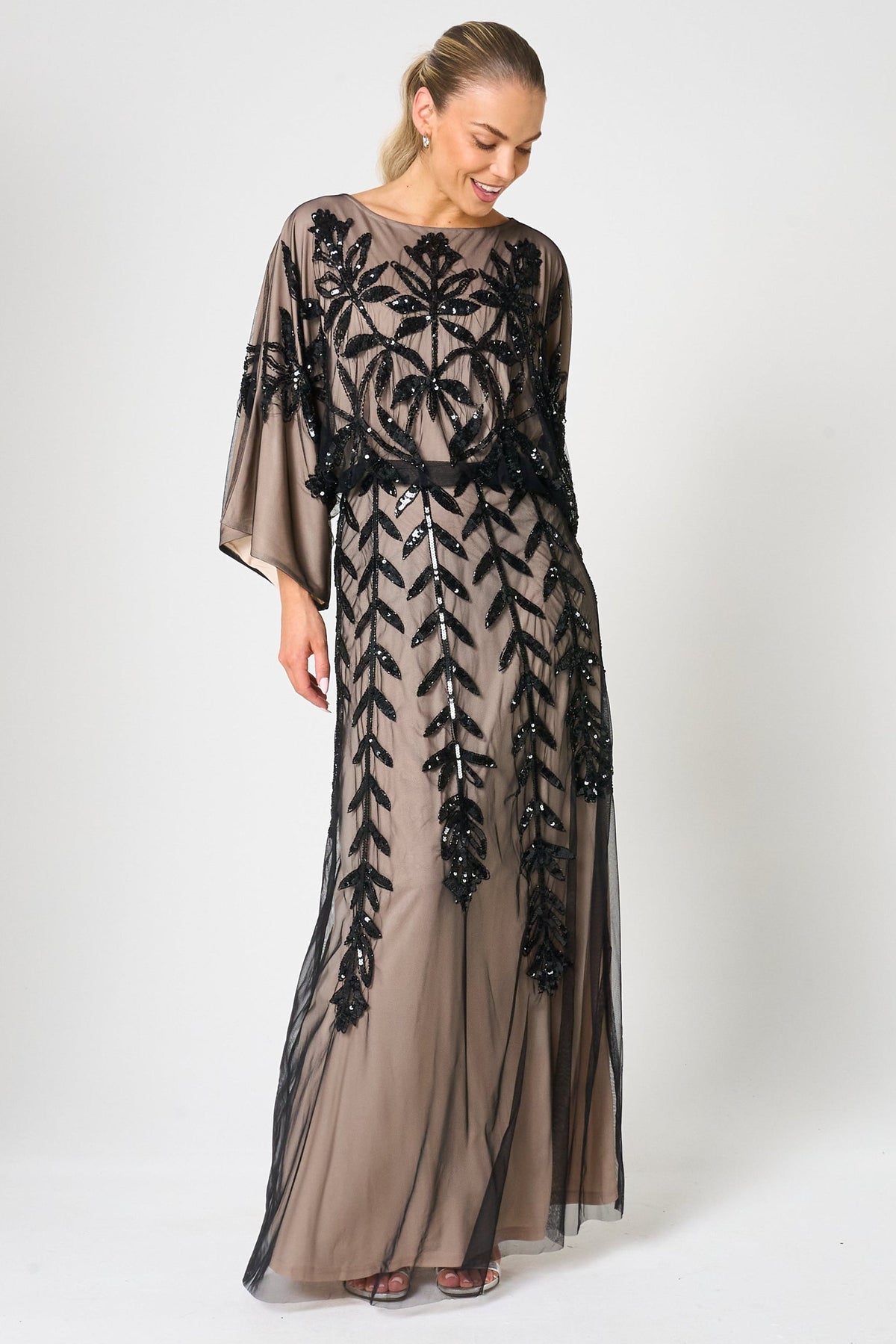 Elva sequin maxi dress with black leaf motif embellishment on a neutral base, batwing sleeves and flowing silhouette for statement occasion wear styling