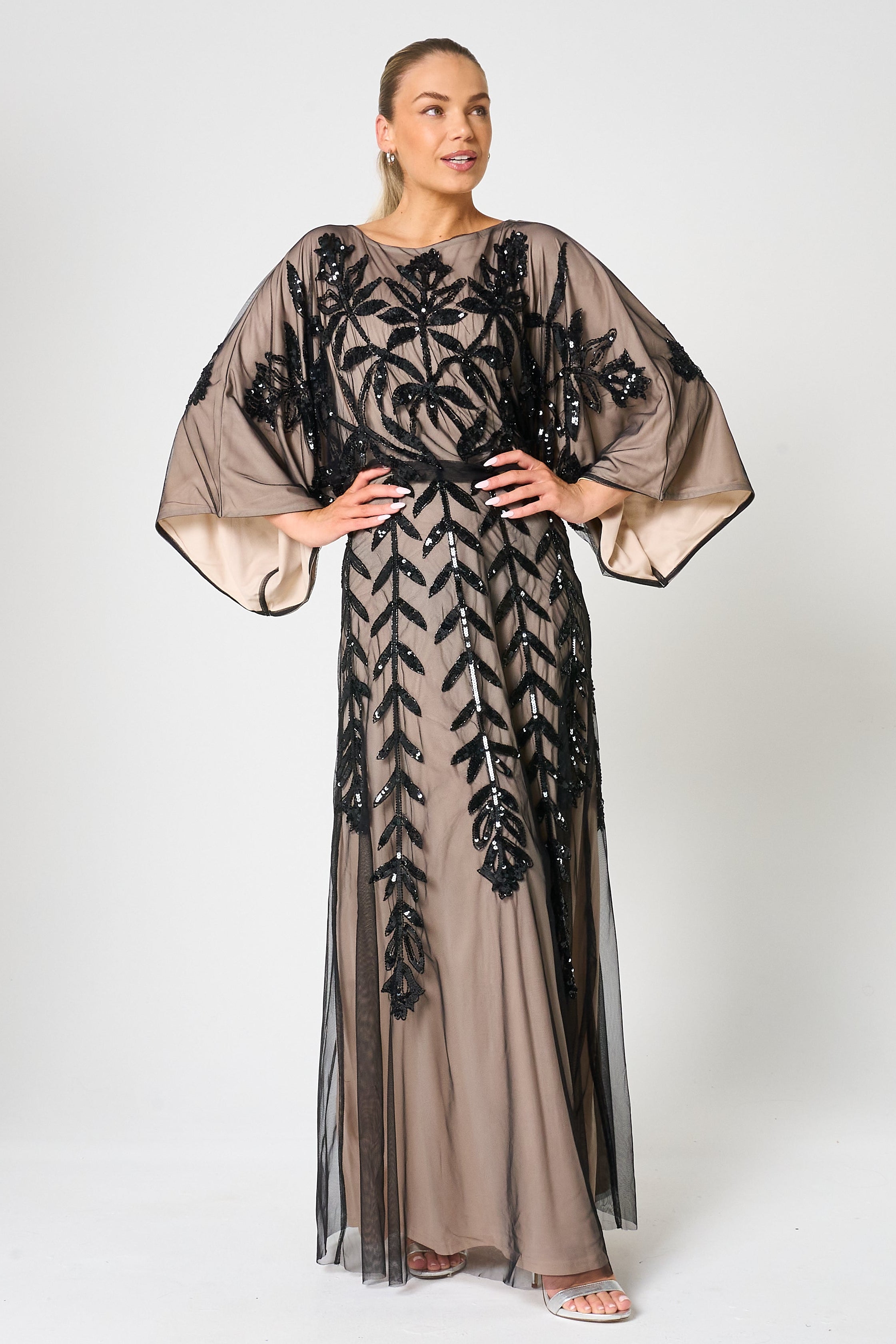 Elva sequin maxi dress with black leaf motif embellishment on a neutral base, batwing sleeves and flowing silhouette for statement occasion wear styling