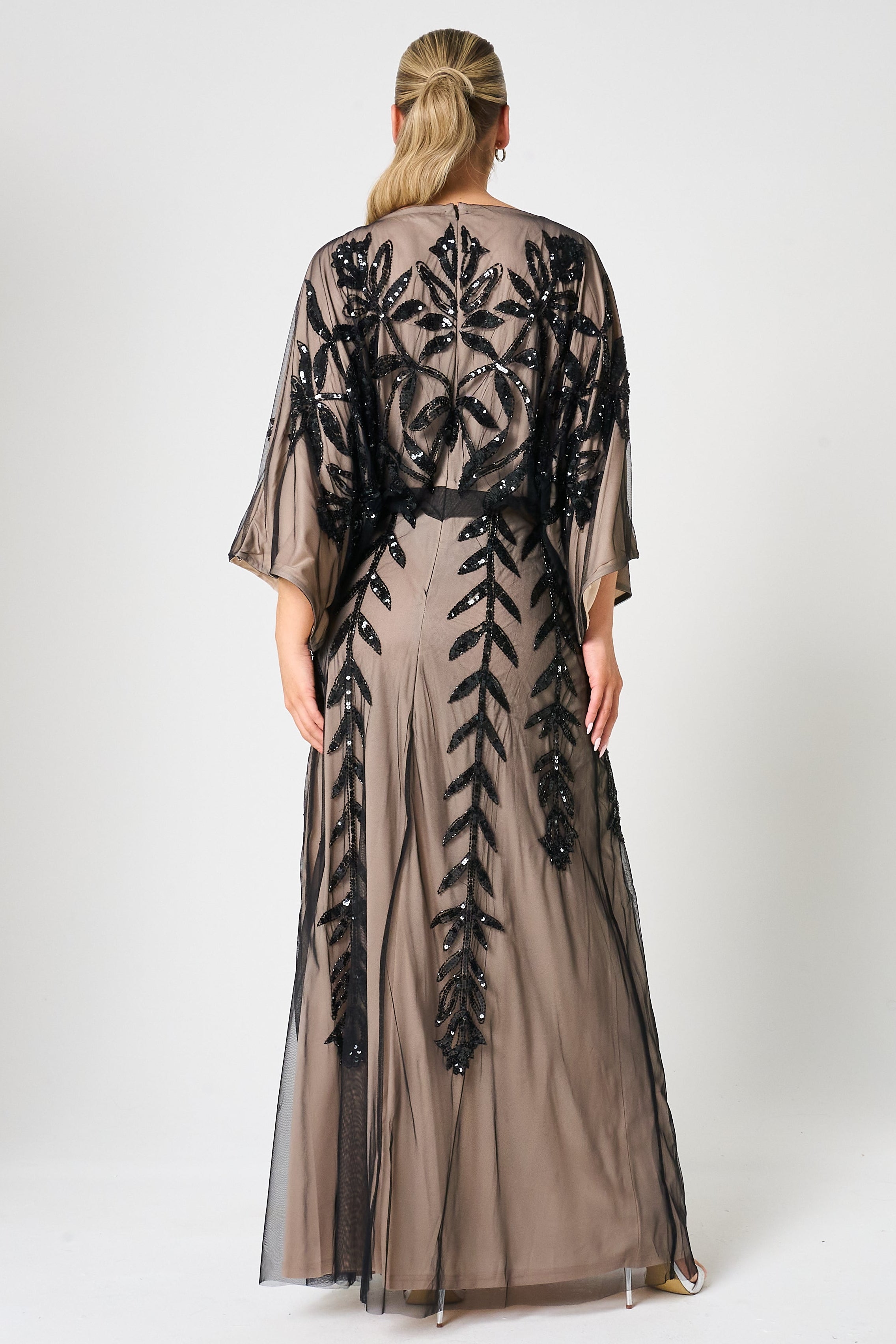 Elva sequin maxi dress with black leaf motif embellishment on a neutral base, batwing sleeves and flowing silhouette for statement occasion wear styling