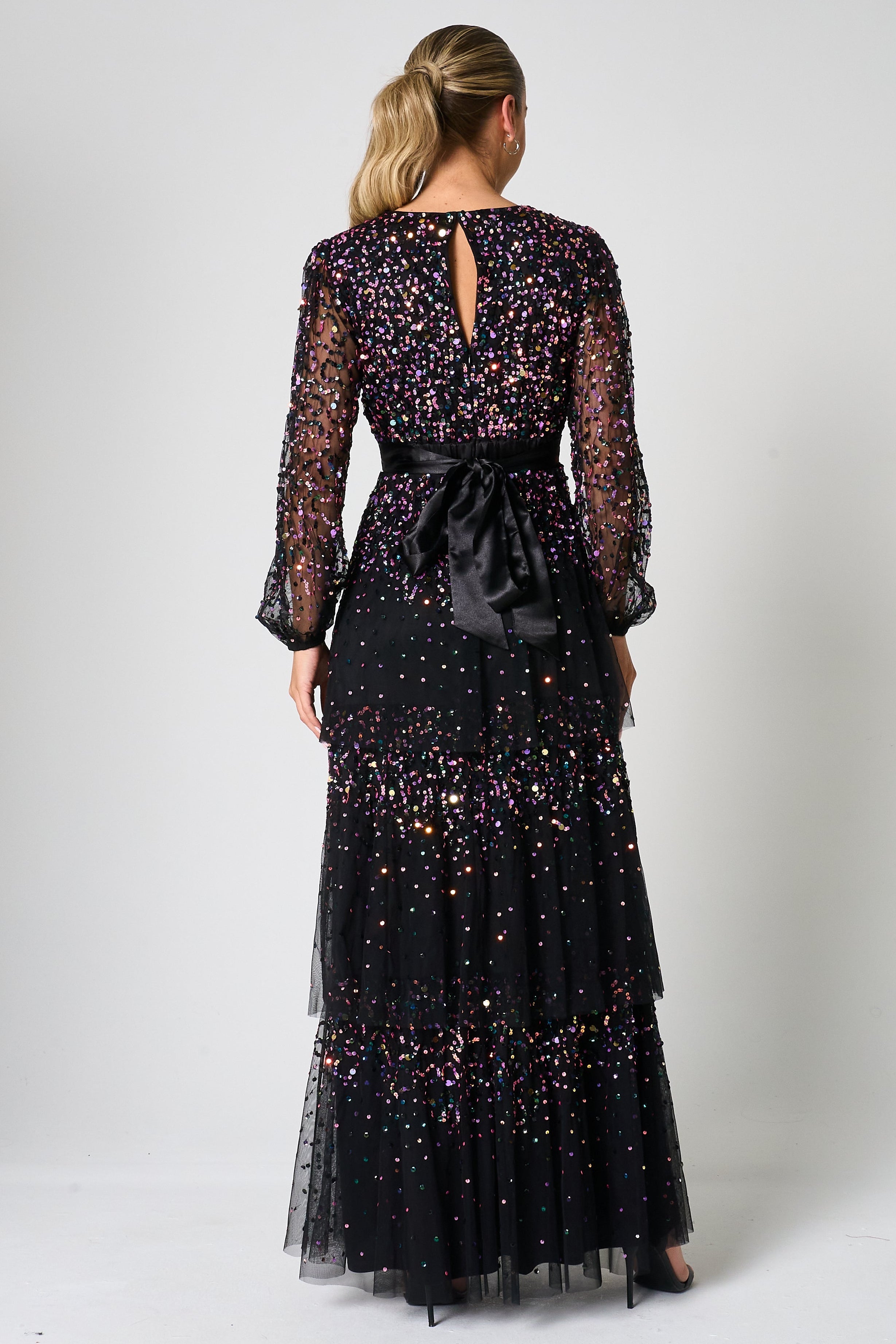 Iris black iridescent sequin maxi dress with V neckline, sheer sleeves and tiered skirt designed for elegant evening and occasion wear styling