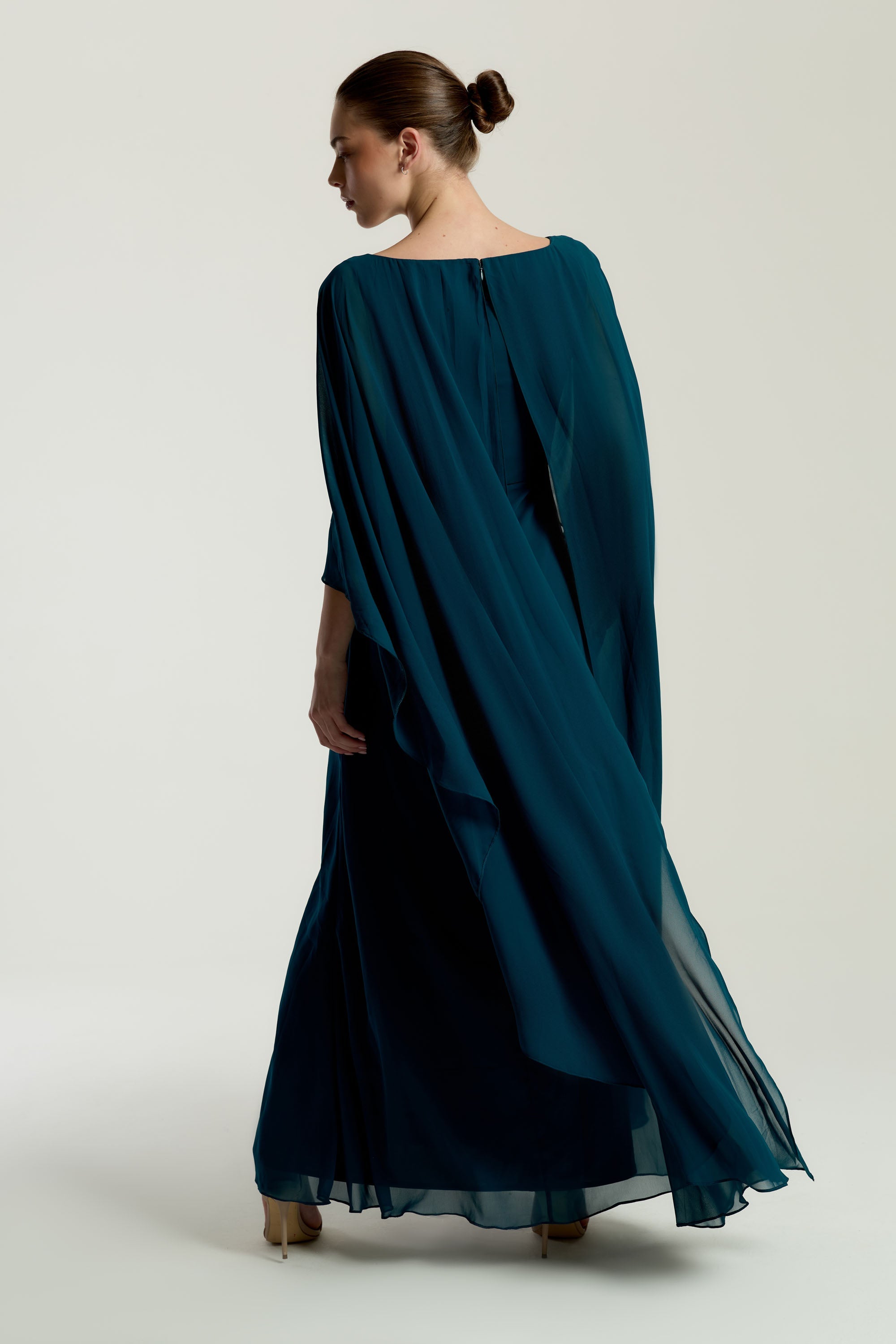 Rhea teal cape sleeve maxi dress with silver-embellished bodice, flowing cape overlay, and modest elegant silhouette for weddings and formal events.