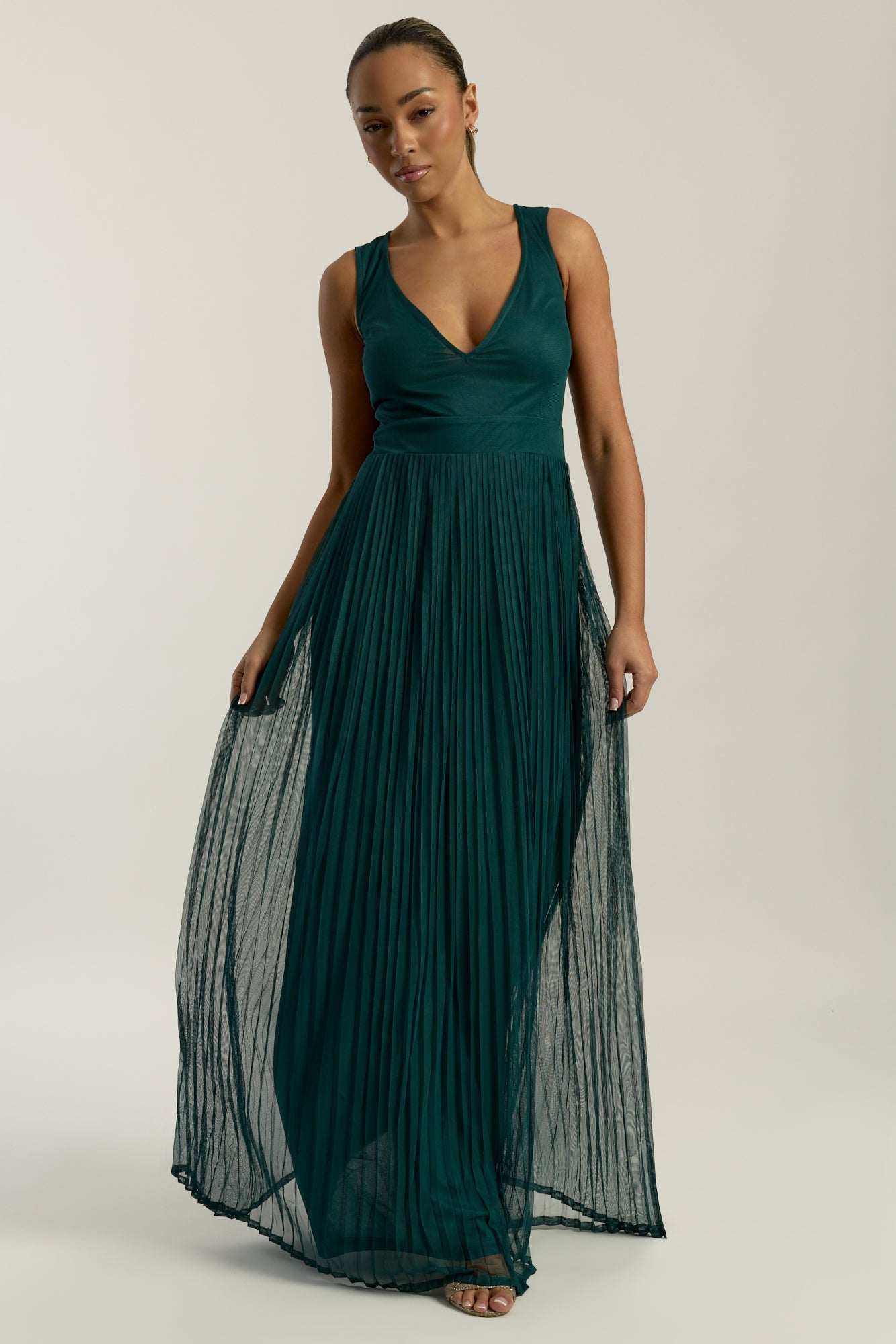 Green embellished maxi dress with flowing pleated skirt and detachable sheer cape overlay, featuring gold bead detailing and an elegant V-neck silhouette for occasion wear.