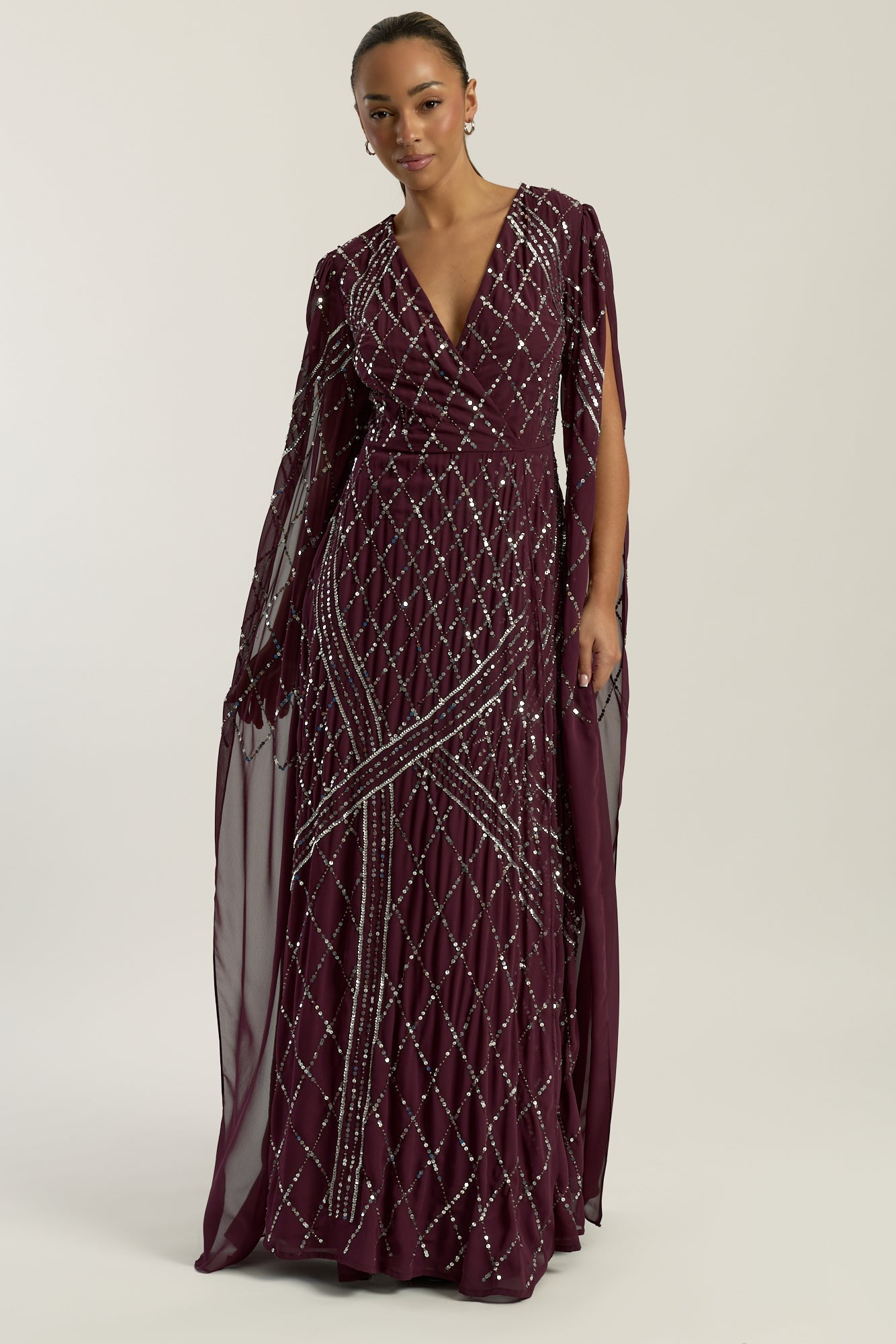 Simone fig sequin cape sleeve maxi dress with plunging V neckline, silver criss-cross sequin detailing and flowing full-length silhouette for statement occasion wear styling