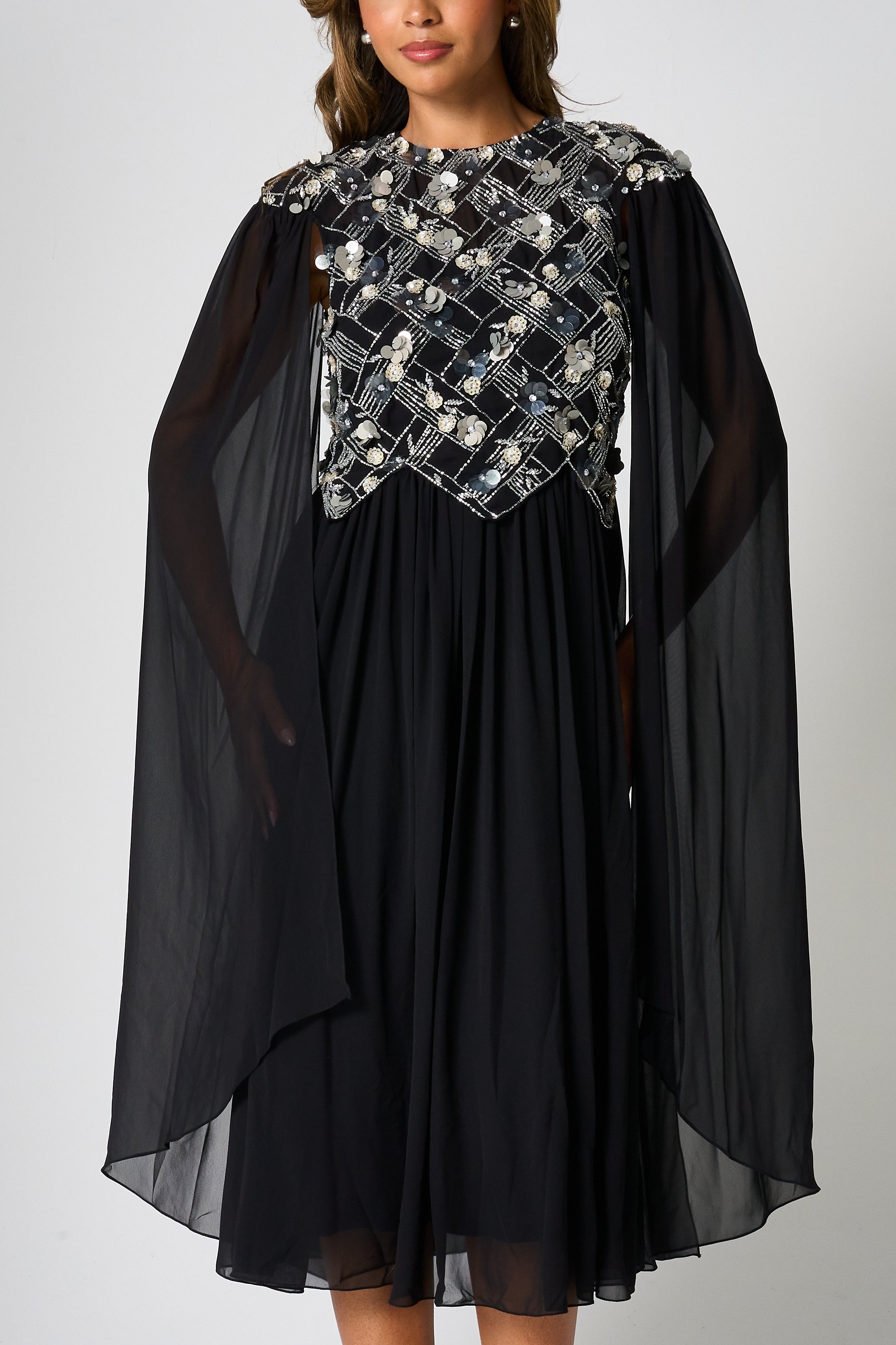 Una black embellished cape sleeve midi dress by Frock and Frill with silver bodice detailing, high neckline and flared skirt designed for elegant occasion wear styling