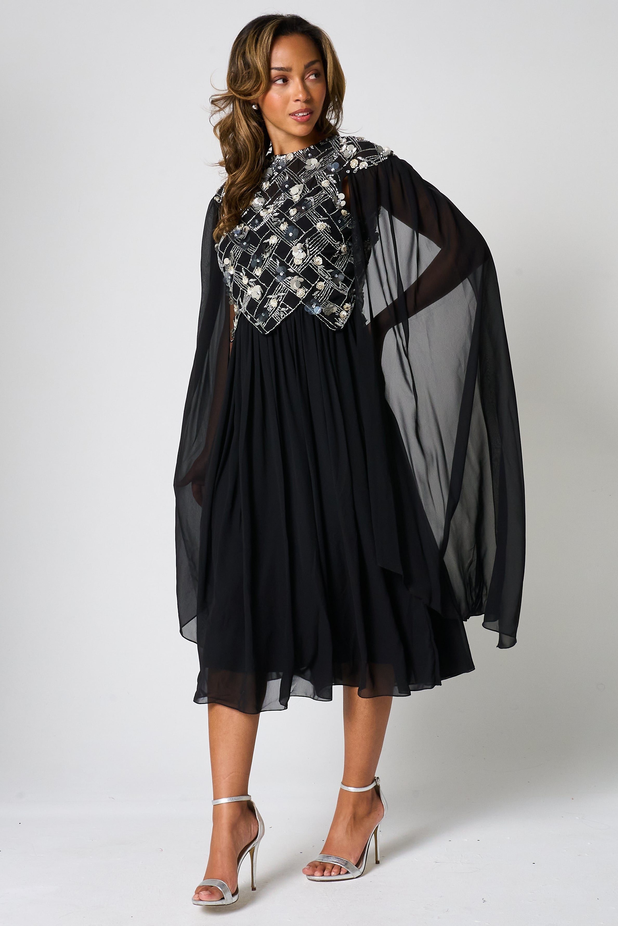 Una black embellished cape sleeve midi dress by Frock and Frill with silver bodice detailing, high neckline and flared skirt designed for elegant occasion wear styling