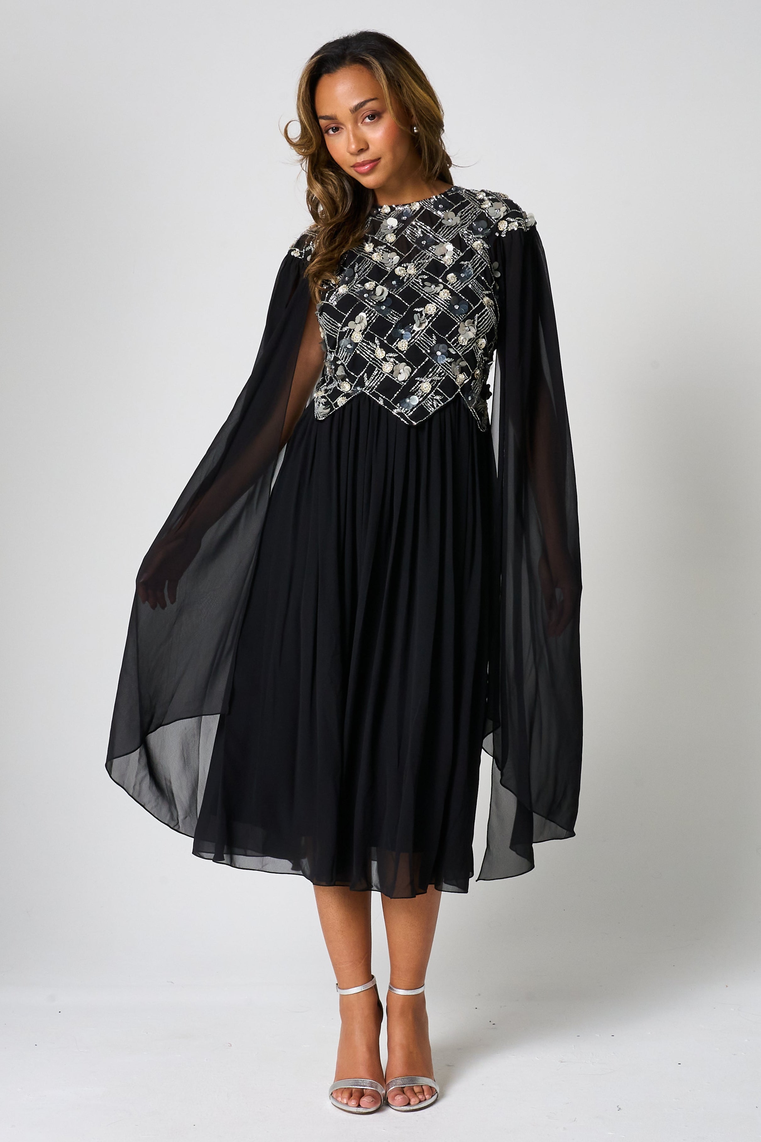 Una black embellished cape sleeve midi dress by Frock and Frill with silver bodice detailing, high neckline and flared skirt designed for elegant occasion wear styling