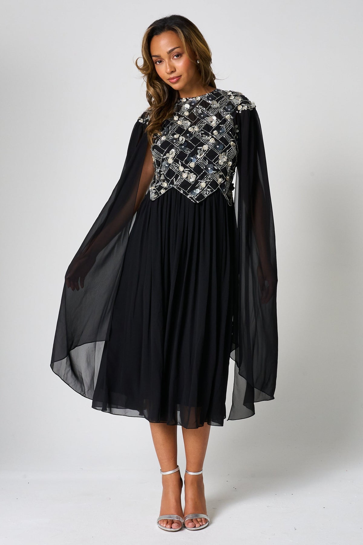 Una black embellished cape sleeve midi dress by Frock and Frill with silver bodice detailing, high neckline and flared skirt designed for elegant occasion wear styling